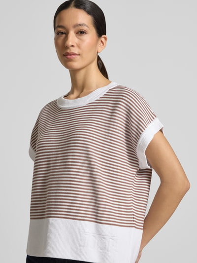 Frauenmodel trägt T-Shirt aus reiner Baumwolle in Strick-Optik Modell 'Kipe' von JOOP!, braun-weiß gestreift, lockere Passform, Rundhalsausschnitt, Label-Detail, Nahaufnahme Oberkörper.