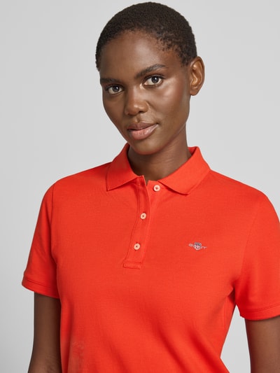 Frauenmodel trägt Poloshirt mit Logo-Stitching und Polokragen von Gant in Rot, Reine Baumwolle, Regular-Fit, Nahaufnahme Oberkörper.