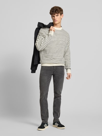Männermodel trägt Slim Fit Jeans aus Baumwoll-Mix Modell 'LOOM' von Only & Sons, unifarbenes Denim mit Label-Applikationen, Ganzkörperansicht von vorne.