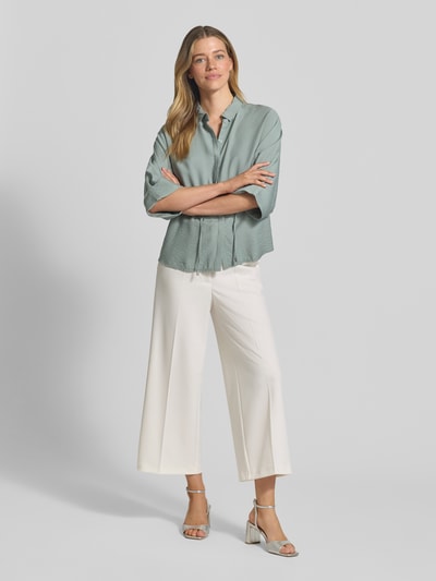 Modelka nosi spodnie materiałowe Wide Fit Stoffhose mit Bügelfalten Modell 'Juli' od Betty Barclay, elastyczna mieszanka materiałów, kanty, zapięcie na haftkę i zamek błyskawiczny, szerokość w rozmiarze 36: 35 cm, długość wewnętrzna nogawki w rozmiarze 36: 64 cm, widok całej sylwetki od przodu.
