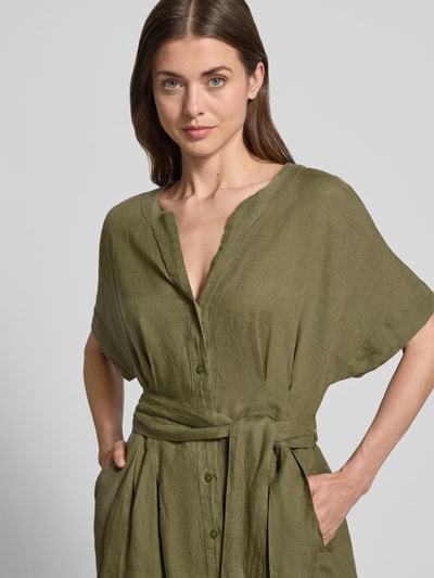 Frauenmodel trägt Midikleid aus reinen Leinen mit Tunika-Ausschnitt Modell 'Soli' von Christian Berg Woman Selection, olivgrün, taillierte Passform, kurze Ärmel, durchgehende Knopfleiste, abnehmbares Stoffband, leichte Leinenstruktur, Nahaufnahme Oberkörper.