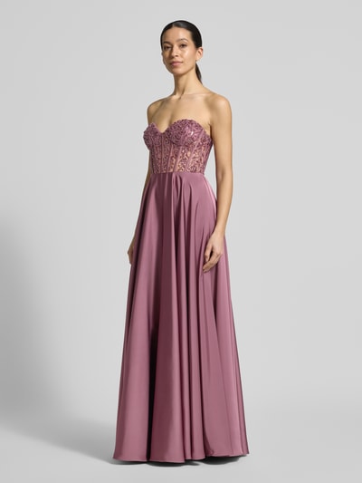 Modelka nosi Abendkleid mit Ziersteinbesatz von Laona w kolorze śliwkowym, A-linia, dekolt serce, optyka gorsetowa, ozdobne marszczenia, zamek z tyłu, długość pleców w rozmiarze 36: 130 cm, szerokość w rozmiarze 36: 36 cm, maxi, całkowity widok z przodu.