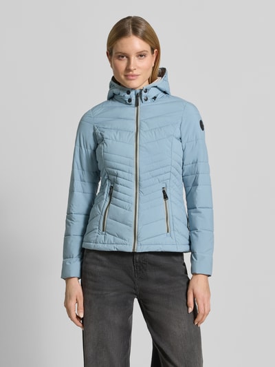 Vrouwenmodel draagt Slim Fit Jacke in Stepp-Optik van G.I.G.A. DX in lichtblauw met afneembare capuchon, logo-detail, rits en steekzakken met rits, stof met gestikte structuur, maat 36: ruglengte 60 cm, schouderbreedte 45 cm, borstwijdte 46 cm, mouwlengte 64 cm. Vooraanzicht van het volledige lichaam.