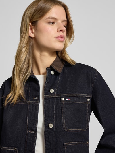 Frauenmodel trägt Oversized Jeansjacke aus reiner Baumwolle von Tommy Jeans in Dunkelblau mit Label Stitching, Nahaufnahme Oberkörper.