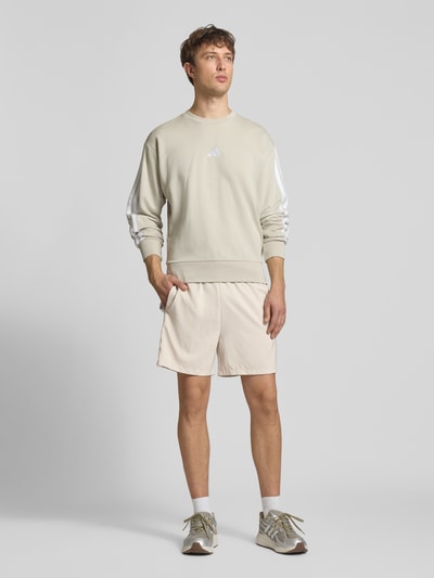 Männermodel trägt Regular Fit Sport-Shorts mit Kontraststreifen von adidas Sportswear, unifarben, elastischer Bund, Ganzkörperansicht von vorne.