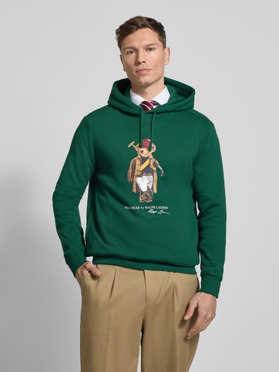 Männermodel trägt Regular Fit Hoodie aus Baumwoll-Mix von Polo Ralph Lauren, Optik: Unifarben, Motiv-Print, Ganzkörperansicht von vorne.
