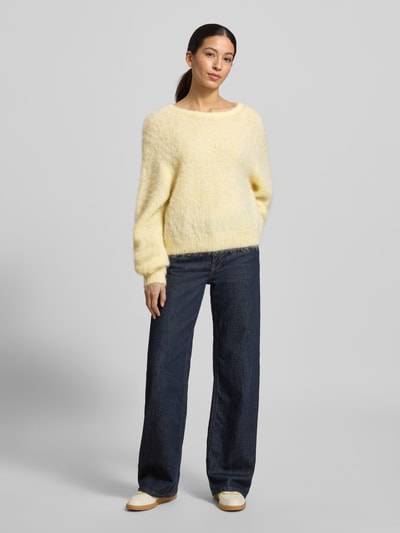 Modelka nosi Strickpullover mit gerippten Abschlüssen Modell 'NIBY' od American Vintage, luźny krój, okrągły dekolt, żółty, dżinsy, pełny widok z przodu