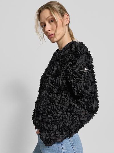 Frauenmodel trägt Blouson mit Label-Patch Modell 'JADE' von Frieda & Freddies, Schwarz, strukturierte 3D-Blumen-Textur, Nahaufnahme Oberkörper. Rückenlänge 53 cm, Schulterbreite 40 cm, Brustweite 50 cm, Ärmellänge 65 cm, Gerader-Schnitt, Stehkragen, Zweiwege-Reißverschluss, Gerippter Saumabschluss.