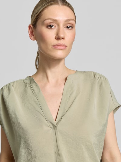 Vrouwenmodel draagt Blusenshirt aus Modal-Mix model 'Sawoko' van OPUS in lichtgroen, relaxed fit, V-hals, gladde textuur, nahaufnahme bovenlichaam. Ruglengte maat 36: 56 cm, mouwlengte maat 36: 16 cm.