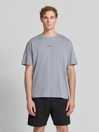Męski model nosi Relaxed Fit T-Shirt aus reiner Baumwolle Modell 'TEE 10' od BOSS Green w jasnoszarym kolorze, gładka faktura, Ganzkörperansicht von vorne.