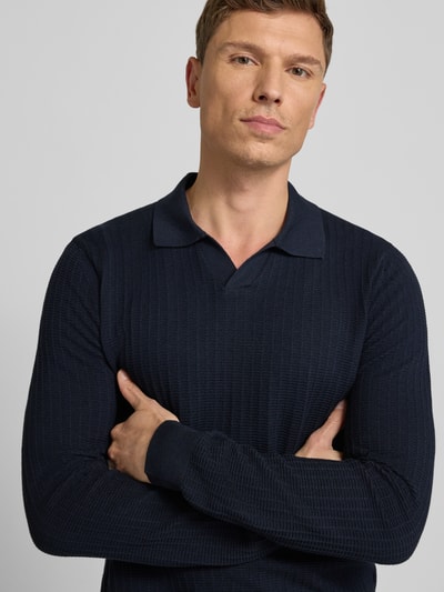 Männermodel trägt dunkelblauen Strickpullover mit Umlegekragen Modell 'Galdino' von JOOP! Collection, Baumwoll-Mix, Strukturmuster, Nahaufnahme Oberkörper.