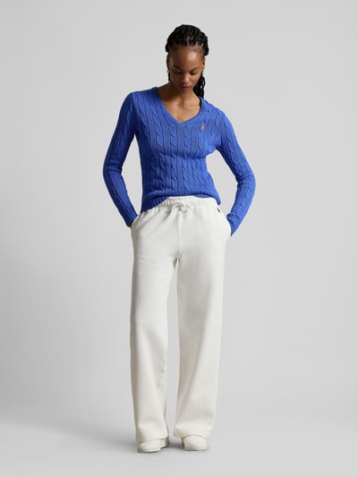 Vrouwenmodel draagt Regular Fit Strickpullover aus Woll-Kaschmir-Mix van Polo Ralph Lauren, blauw, kabelmotief, logo, geribde afwerking, volledig lichaamsaanzicht van voren.