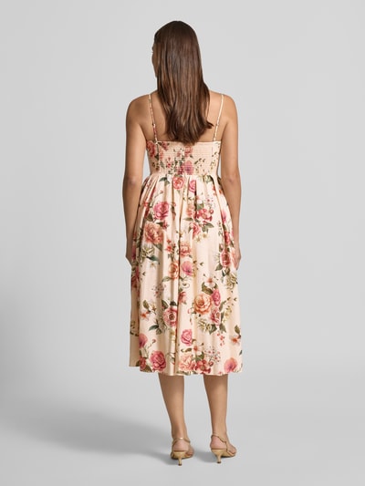 Frauenmodel trägt Midikleid aus Leinen-Viskose-Mix mit Eingrifftaschen von Guess, florales Muster in Rosé und Grün, Ganzkörperansicht Rückansicht. Taillierter Schnitt, Modell 'BRIA' mit Spaghettiträgern, Herz-Ausschnitt, Rückenlänge 94 cm bei Größe S, Brustweite 40 cm, sanft fallender Stoff.