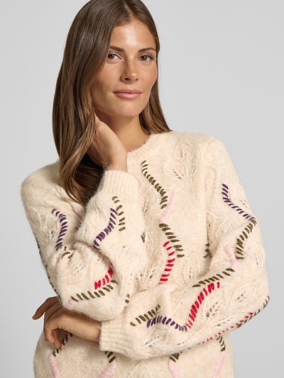 Vrouwenmodel draagt pullover met kabelpatroon van Model 'GABBI' van YAS, materiaalmix met wol, recht model, ronde hals, detailopname bovenlichaam.