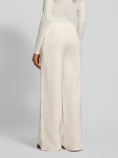 Kobiece modelka nosi luźne, kremowe Guess Activewear Sweatpants mit elastischem Bund Modell 'OCTAVIA', widok całej sylwetki z tyłu.