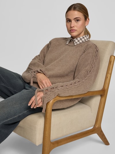 Frauenmodel trägt Oversized Sweatshirt aus Woll-Mix von ROTATE in Beige mit Strick-Optik, Flecht-Detail und Rundhalsausschnitt, Nahaufnahme Oberkörper. Rückenlänge bei Größe S: 65 cm.