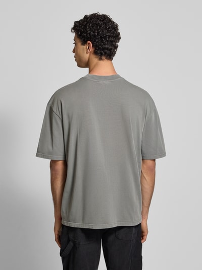 Männermodel trägt Oversized T-Shirt mit Label-Stitching von Pegador aus reiner Baumwolle, Rückenlänge 69 cm, Ganzkörperansicht Rückansicht.