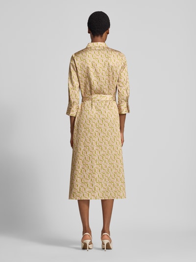 Modelka kobieca nosi Fließendes Freizeitkleid mit Allover-Muster Modell '263D32Diandra2' od JOOP! w odcieniach beżu i zieleni, wzór geometryczny, długość midi, tekstura lekko połyskująca, sukienki casualowe, widok całej sylwetki od tyłu.