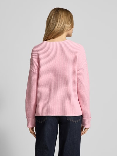 Modelka nosi Oversized Strickpullover aus Baumwoll-Mix od s.Oliver RED LABEL, różowy, jednolity, krój oversize, dekolt V, rękawy 3/4, prążkowany splot, bawełniany miks, widok całej sylwetki z tyłu.