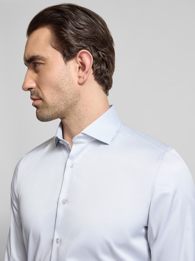 Männermodel trägt Slim Fit Business-Hemd in unifarbenem Design mit Kentkragen von OLYMP Level Five aus reiner Baumwolle, Nahaufnahme Oberkörper.