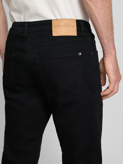 Männermodel trägt schwarze Slim Fit Jeans im klassischen Five-Pocket-Design von REVIEW aus reiner Baumwolle, Detailaufnahme Rückansicht.