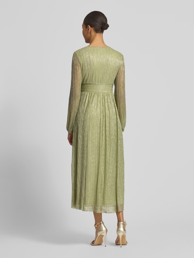 Frauenmodel trägt Tailliertes Freizeitkleid mit Unterkleid von s.Oliver BLACK LABEL in Grün mit Metalic-Optik und Crinkle-Optik, Midi-Länge, Langarm, Ganzkörperansicht Rückansicht.