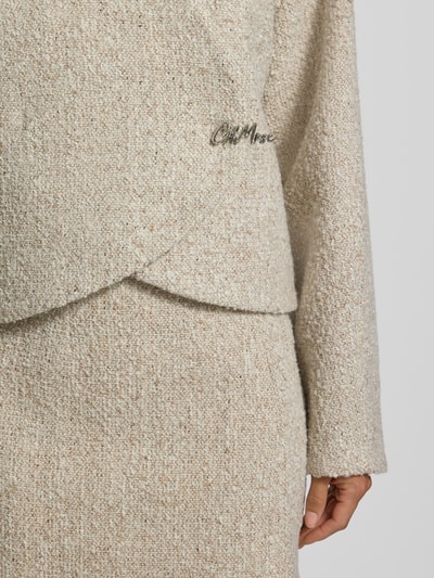 Frauenmodel trägt Blazer in Bouclé-Optik mit Woll-Anteil von Oui, beige strukturierte Oberfläche, Label-Detail, Nahaufnahme Oberkörper. Material-Mix, gerade Passform, Rückenlänge 50 cm, Brustweite 52 cm, Ärmellänge 62 cm.