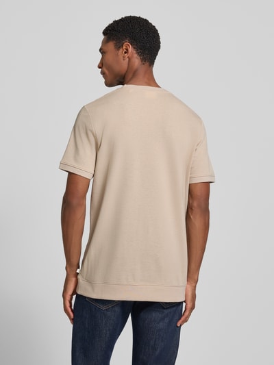 Männermodel trägt Regular Fit T-Shirt aus Baumwoll-Mix von s.Oliver RED LABEL in Beige, glatte Struktur, Ganzkörperansicht Rückansicht.