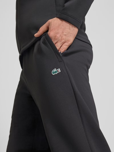 Männermodel trägt Tapered Sweatpants mit Baumwoll-Anteil von Lacoste, efekt: jednolity kolor, krój tapered, naszywka z logo, tunel, elastyczny ściągacz, boczna kieszeń zapinana na zamek błyskawiczny, wykończenie materiału: scuba, Nahaufnahme biodra