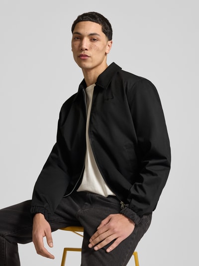 Männermodel trägt schwarze Jacke mit Zweiwege-Reißverschluss Modell 'CATSKILLS' von Jack & Jones, Regular-Fit, Umlegekragen, Label-Stitching, Nahaufnahme Oberkörper, Rückenlänge 64 cm, Schulterbreite 49 cm, Brustweite 59 cm, Ärmellänge 66 cm.