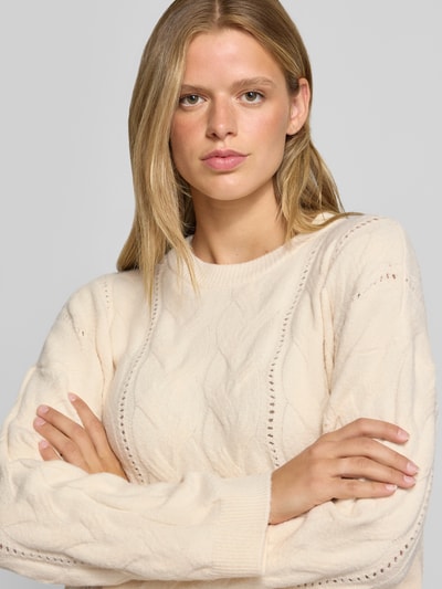 Frauenmodel trägt cremefarbenen Relaxed Fit Pullover mit Rundhalsausschnitt Modell 'KATHY' von PIECES, Damen Pullover, Nahaufnahme Oberkörper.