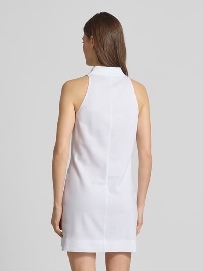 Frauenmodel trägt Slim Fit Polokleid aus Baumwoll-Mix von Lacoste Sport, unifarben weiß, Mini-Länge, Seitenschlitz, Ganzkörperansicht Rückansicht.