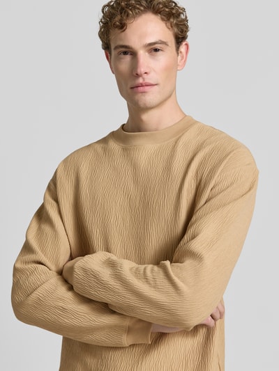 Mężczyzna nosi Regular Fit Sweatshirt aus Baumwoll-Mix model 'DENOLONG' od HUGO, kolor beżowy, faktura prążkowana, z przodu, zdjęcie zbliżenie na górną część ciała.
