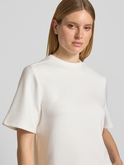 Frauenmodel trägt Relaxed Fit T-Shirt mit Rundhalsausschnitt Modell 'Maelee' von MSCH Copenhagen, Damen T-Shirt in Creme, Halbarm, glatte Textur, Rückenlänge bei Größe XS/S 53 cm, Nahaufnahme Oberkörper.