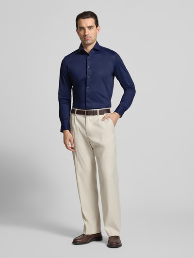 Mannenmodel draagt Slim Fit Business-Hemd mit Haifischkragen van SEIDENSTICKER in donkerblauw, lange mouwen, mix met stretch, knoopsluiting, voorkant volledig zichtbaar, geheel lichaam van voren.