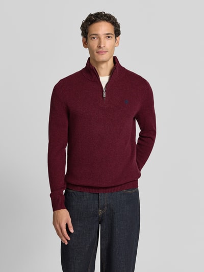 Männermodel trägt Regular Fit Strickpullover aus reiner Wolle von MCNEAL in Bordeaux mit Logo-Stickerei, Troyer-Kragen, Langarm, gerippte Bündchen, Ganzkörperansicht von vorne.