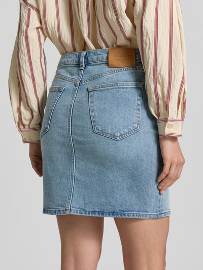 Frauenmodel trägt Jeansrock mit Eingrifftaschen von Gant, Baumwoll-Elasthan-Mix, Gerader-Schnitt, Minirock, hellblau, Ganzkörperansicht Rückansicht.