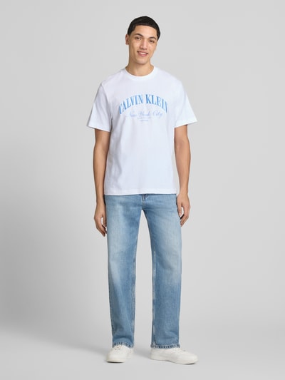Männermodel trägt T-Shirt mit Label-Stitching von Calvin Klein Jeans in Weiß, Reine Baumwolle, Slim-Fit, Rundhalsausschnitt, Herren T-Shirt, Rückenlänge bei Größe M 70 cm, Ganzkörperansicht von vorne.