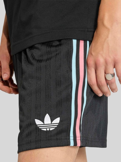 Männermodel trägt Regular Fit Sweatpants mit Label-Detail Modell 'RBFA OG SHO' von adidas Originals, Optik: Unifarben, Materialverarbeitung: Sweat, Nahaufnahme Oberschenkel.
