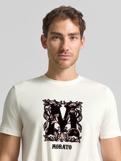 Männermodel trägt Regular Fit T-Shirt aus reiner Baumwolle von Antony Morato, cremeweiß mit Label-Print, Nahaufnahme Oberkörper.