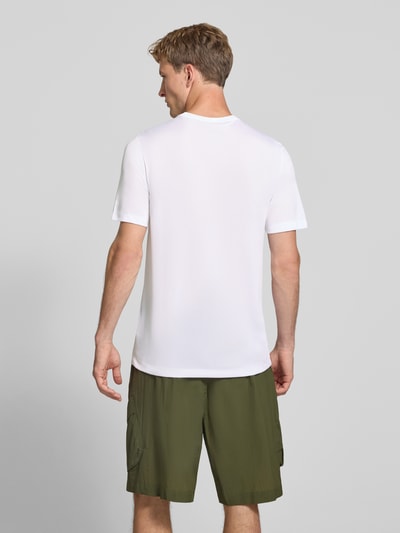 Männermodel trägt T-Shirt mit Logo-Print und Rundhalsausschnitt von NIKE TRAINING in Weiß, glatte Textur, Ganzkörperansicht Rückansicht. Rückenlänge bei Größe M: 66 cm, gerader Schnitt, Regular Fit.