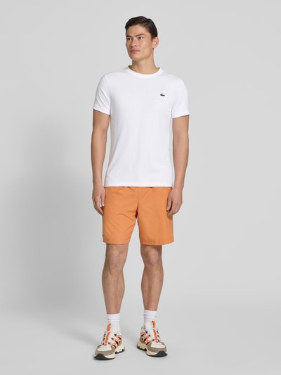 Männermodel trägt weißes Regular Fit T-Shirt aus Baumwoll-Mix von Lacoste Sport mit Logo-Patch, unifarben, Ganzkörperansicht von vorne