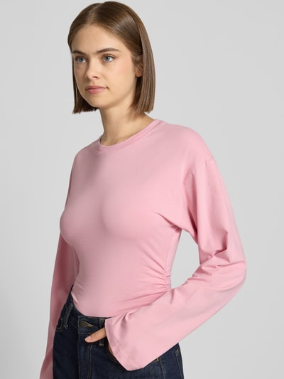 Modelka nosi bluzkę z długim rękawem z mieszanki bawełny, taliowany krój, okrągły dekolt, model 'Paloma' od JJXX, długość tyłu 57 cm w rozmiarze S, widok na cały przód.