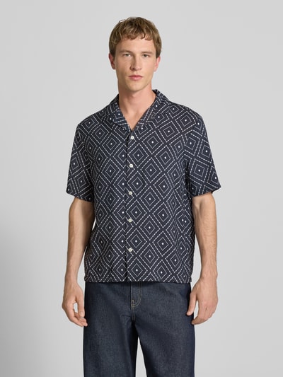 Männermodel trägt Modern Fit Freizeithemd aus Viskose-Mix mit Reverskragen von REVIEW, schwarz mit geometrischem Muster, Nahaufnahme Oberkörper.