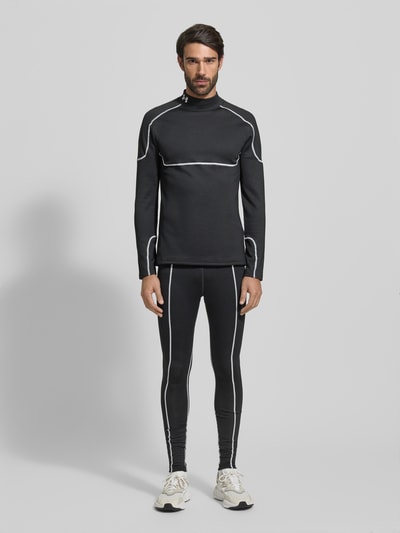 Männermodel trägt Leggings mit elastischem Bund und Label-Details von Under Armour im Material-Mix mit Stretch-Anteil, körpernahe Passform, Label-Details, schwarze Farbe mit weißen Nähten, Innenbeinlänge bei Größe M 78 cm, Ganzkörperansicht von vorne.
