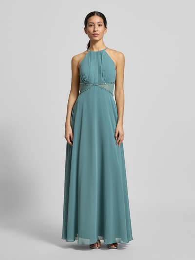 Kobiece modelka nosi Regular Fit Sukienka wieczorowa z obszyciem ozdobnymi kamieniami od Jake*s Cocktail, półprzezroczyste partie, taliowany krój, wiązanie na szyi, plisy, halka, długość tyłu 156 cm, szerokość klatki piersiowej 38 cm, kolor morski, gładka tkanina, widok całej sylwetki z przodu.