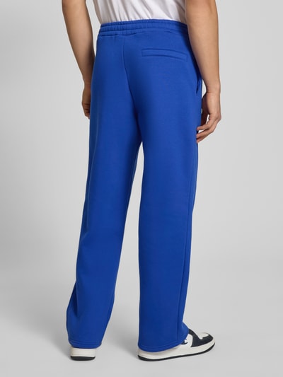 Mannenmodel draagt Sweatpants met elastische band van REVIEW in felblauw, materiaalmix met katoen, relaxed fit, achterzak, geheel van achteren.