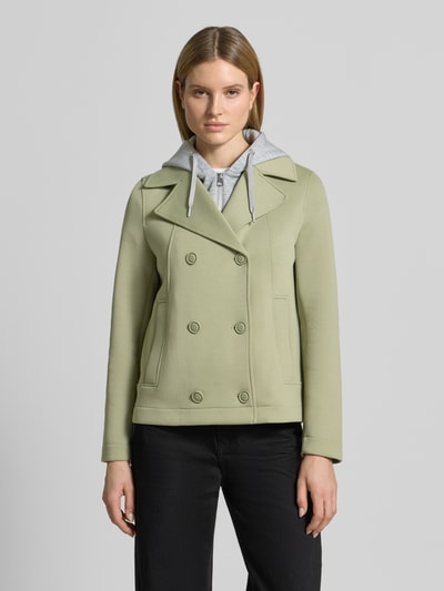 Vrouwenmodel draagt Regular Fit sweatjack met viscose van s.Oliver RED LABEL in lichtgroen, met reverskraag, capuchon en steekzakken, materiaalverwerking sweat, lange mouw, dubbele knoopsluiting, sluiting met verborgen ritssluiting. Volledige vooraanzicht.