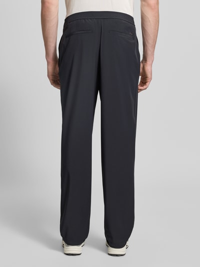 Męski model nosi Hose mit elastischem Bund und Gesäßtaschen od ARMANI EXCHANGE, czarny materiał z dodatkiem stretchu, krój relaxed fit, elastyczny pas, tylne kieszenie, szerokość w rozmiarze 32: 40 cm, długość wewnętrzna nogawki w rozmiarze 32: 79 cm, zdjęcie całej sylwetki z tyłu.