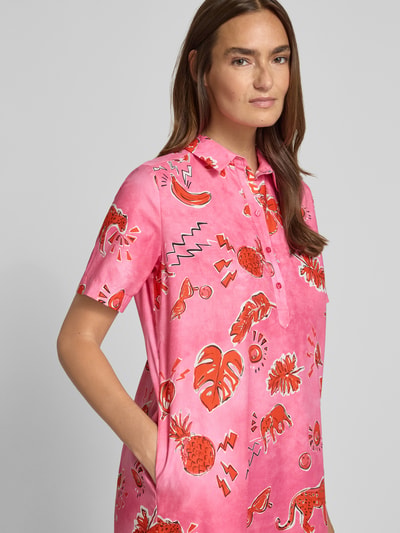 Kobiece model prezentuje sukienkę koszulową 'Knielanges Hemdblusenkleid mit kurzer Knopfleiste' od Milano Italy z bawełny, krój straight fit, długość do kolan, kołnierzyk koszulowy, krótka listwa guzikowa, długość tyłu w rozmiarze 36: 96 cm, szerokość w rozmiarze 36: 53 cm, długość rękawów w rozmiarze 36: 25 cm, różowy wzór z czerwonymi grafikami, gładka tekstura, pełny widok z przodu.